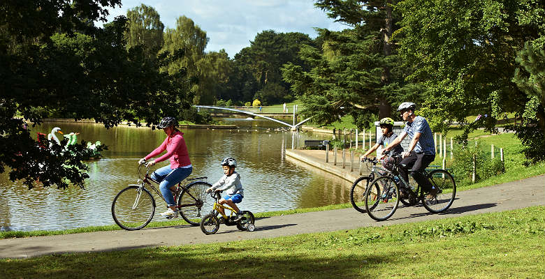 A group of cyclist riding near a lake