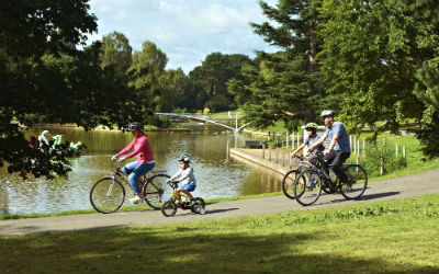 Cyclists riding around a lake ion Crewe Park