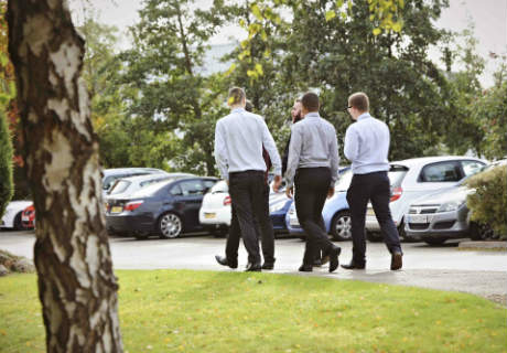 Five men walking through a car park