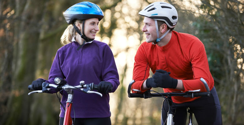 A woman and man on bicycles wearing cycle helmets