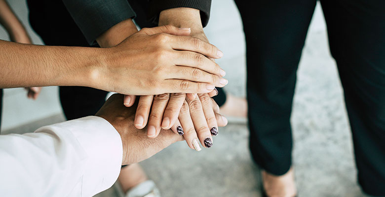 Close up of young business people putting and join their hands together. Team with stack of hands showing unity, collaboration and teamwork